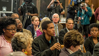 Image of young man with microphone speaking during a news conference